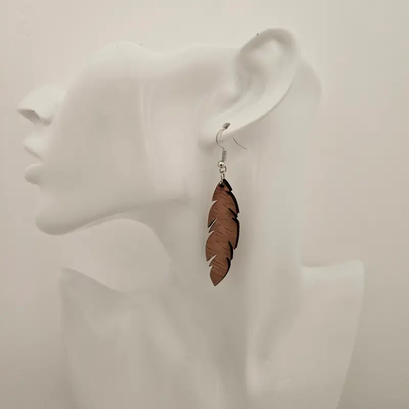 Paire de boucles d’oreilles en bois finement sculptées en forme de plume, présentées sur un élégant présentoir.