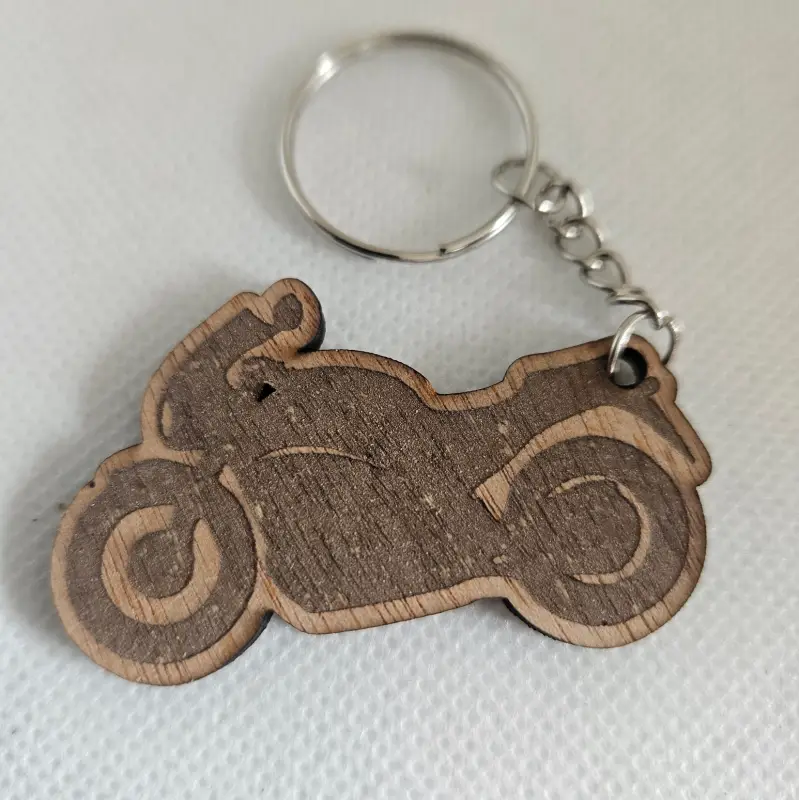 Porte clé en forme de moto découpé et gravé. il est attaché à un anneau métallique.