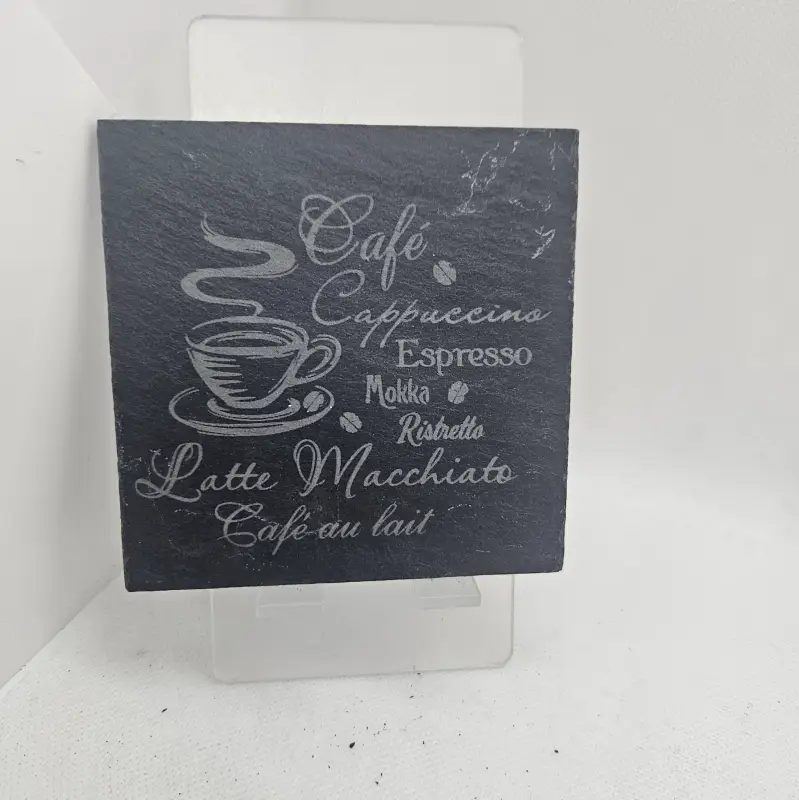 Dessous de verre en ardoise qui représente une tasse qui fume au dessus et les inscriptions : "café, Cappuccino, Espresso, Mokka, Ristretto, Latte Macchiato et Café au lait".